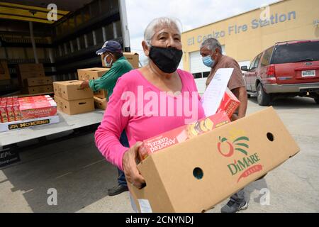 El Cenizo, TX USA 17. September 2020: Lokale Freiwillige, darunter Gloria Romo, verteilen Lebensmittelkisten an die Bewohner der colonia von El Cenizo, etwa 10 Meilen südlich von Laredo entlang der Grenze zwischen Texas und Mexiko. Etwa 450 Familien werden zweimal in der Woche mit Heftklammern und frischem Obst in einer von der lateinamerikanischen lutherischen Mission (LALM) gesponserten Bemühung serviert. Aufgrund der Coronavirus-Pandemie ist die Verteilung nun ein sozial distanziertes Drive-Through-Ereignis, bei dem Freiwillige und Kunden alle Gesichtsbezüge tragen. Kredit: Bob Daemmrich/Alamy Live Nachrichten Stockfoto