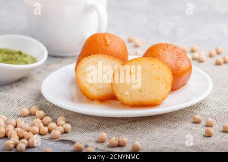 Traditionelle indische Süßigkeiten Gulab Jamun in weißem Teller mit Minze Chutney auf einem grauen Beton Hintergrund. Seitenansicht, close up. Stockfoto