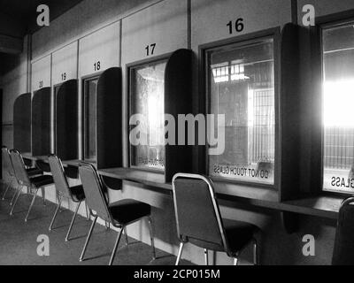 Schwarz-Weiß-Ansicht im geschlossenen Gefängnis Besuchsbereich in einer ungenutzten heruntergekommenen staatlichen Einrichtung. Stockfoto