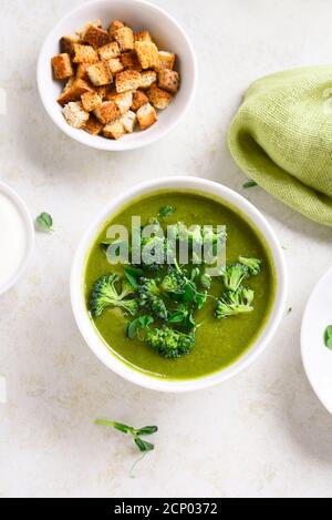 Gesunde Brokkoli grüne Erbsencremensuppe in der Schüssel über hellem Steinhintergrund. Diätdetox-Food-Konzept. Draufsicht, flacher Lay Stockfoto