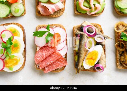 Set von verschiedenen Sandwiches mit Fleisch, Gemüse, Meeresfrüchte auf hellem Stein Hintergrund. Schmackhafter gesunder Snack. Draufsicht, flach liegend, Nahaufnahme Stockfoto