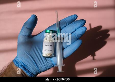 Covid 19 Virus, Gesundheitskonzept mit blauer medizinischer Handschelle mit einem Impfstofffläschchen für die Virusbehandlung Stockfoto