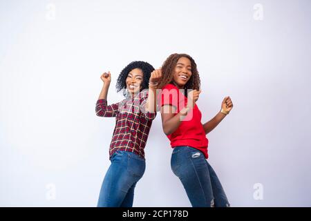 Zwei hübsche junge afrikanische Damen fühlen sich aufgeregt und glücklich, auf weißem Hintergrund Stockfoto