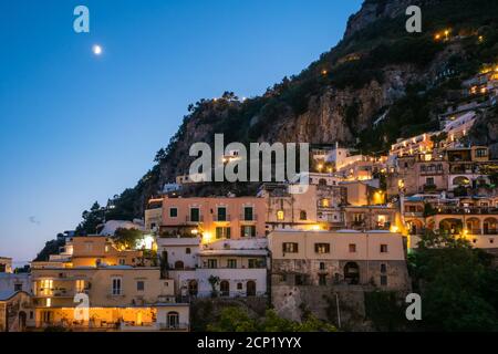 Positano Häuser beleuchtet in der Nacht oder am Abend auf einem Hügel mit Mond Stockfoto