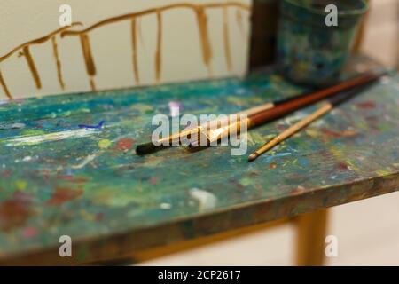 Pinsel auf einer Staffelei mit Farben im Atelier des Künstlers gefärbt. Stockfoto