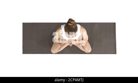 Junge Yogi-Frau, die Yoga praktiziert, Namaste-Geste in Lotus-Pose macht, weißes T-Shirt auf weißem Hintergrund trägt. Stockfoto