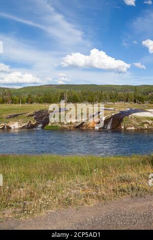 Der Firehole River mit Wasser aus den nahe gelegenen heißen Quellen, die über den Damm und in den Fluss im Yellowstone National Park, Wyoming fließen. Stockfoto