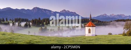 Hegratsrieder Kapelle vor dem Panorama der Ammergauer und Allgäuer Alpen bei Halch, Ostallgäu, Allgäu, Schwaben, Bayern, Süddeutschland, Germ Stockfoto