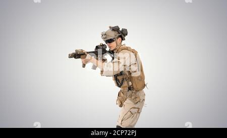 Soldat zielt mit einem Sturmgewehr auf Steigungshintergrund. Stockfoto