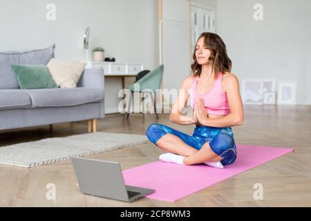 Online-Yoga-Lektion. Meditation vor dem Laptop-Monitor. Stockfoto