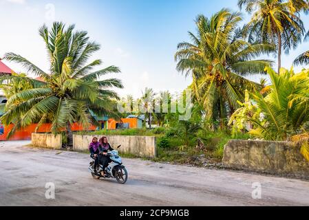 FULAHMULAH, MALEDIVEN - 9. APRIL 2017: Zwei Frauen in muslimischer Kleidung fahren auf der Äquatorialinsel Fulahmulah auf den Malediven im Indischen Ozean mit einem Moped Stockfoto