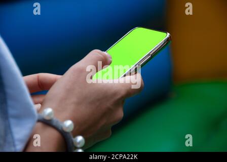 Smartphone mit grünem Chromakey auf dem Bildschirm in den Händen einer Frau. Eine Frau nutzt mobile App auf dem Smartphone mit einem grünen Bildschirm Chromakey. Stockfoto