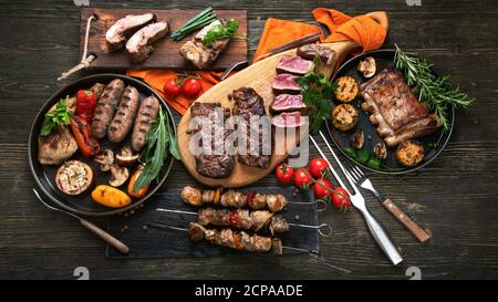 Gemischtes Grillfleisch mit Gemüse auf Holzgrund. Grillmenü. Draufsicht Stockfoto