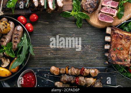 Gemischtes Grillfleisch mit Gemüse auf Holzgrund. Grillmenü. Draufsicht, Kopierbereich. Stockfoto