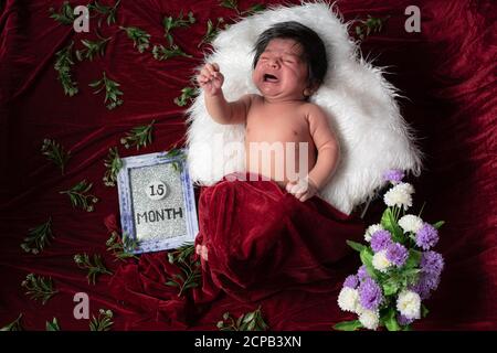 1.5 Monate Baby Junge weinen, während Foto-Shooting ruhen auf Während Kissen und Bezüge mit rotem Samttuch Stockfoto