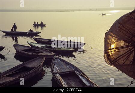 12.02.2004, Varanasi (Benares), Uttar Pradesh, Indien, Asien - Tagesanbruch mit Sonnenaufgang über hölzernen Ruderbooten am Ufer entlang des heiligen Ganges. Stockfoto