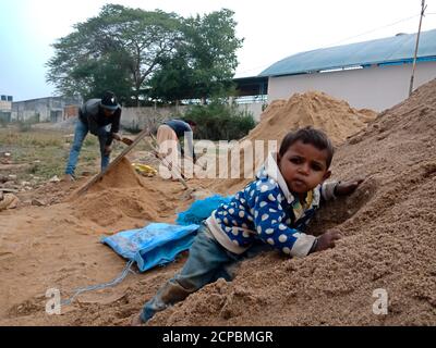 BEZIRK KATNI, INDIEN - 18. DEZEMBER 2019: Ein indisches Dorf arbeitet Kind Klettern auf Sandstock auf Baustelle. Stockfoto