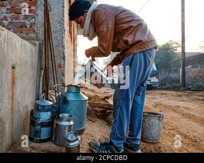 DISTRIKT KATNI, INDIEN - 04. JANUAR 2020: Ein Milchbauer sammelt Milch auf Container in seiner lokalen Milchfarm Außengebiet, eine indische Farmszene. Stockfoto