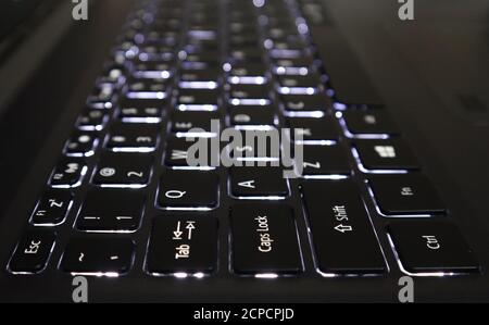 Weiße Tastatur mit Hintergrundbeleuchtung eines Laptops mit selektivem Fokus und unscharfen Hintergrundeffekten. Stockfoto