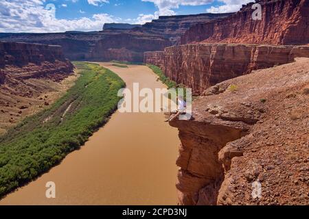 Besucher sitzen auf Felsen Überhang über Colorado River, Potash Road, Canyonlands National Park, Utah, USA Stockfoto