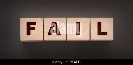 FAIL Word-Text in Holzwürfelblöcken auf schwarzem Hintergrund geschrieben. Krisenkonzept Stockfoto
