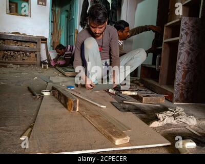 DISTRIKT KATNI, INDIEN - 08. JANUAR 2020: Ein indischer Holzarbeiter Junge hackt Sperrholz in der Werkstatt. Stockfoto