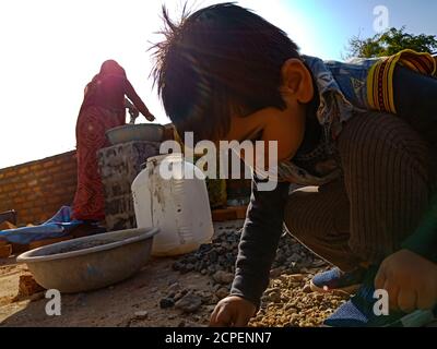 DISTRIKT KATNI, INDIEN - 13. JANUAR 2020: Ein indisches männliches Kind sitzt auf der Baustelle am Himmel Hintergrund. Stockfoto