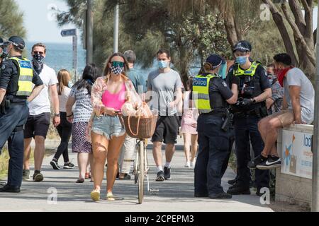 Melbourne, Australien. 19. September 2020. Strandgänger gehen an einem Protestanten vorbei, der verhört wird und von den Victoria Polizeibeamten am Elwood Beach zu einer Geldstrafe von 1600 Dollar verurteilt wurde, nachdem ein Anti-Maske- und Anti-Lockdown-Protest im Elsternwick Park, Melbourne, Australien, begann. Kredit: Michael Currie/Alamy Live Nachrichten Stockfoto