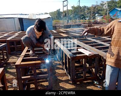 DISTRIKT KATNI, INDIEN - 17. JANUAR 2020: Asiatischer Wartungsarbeiter, der während der Eisenbahnbrückenbauarbeiten am Eisennetz schweißen wird. Stockfoto