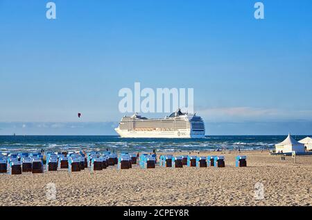 Am Strand mit Liegestühlen und Badegäste vorbei Kreuzfahrtschiff in Warnemünde. Stockfoto