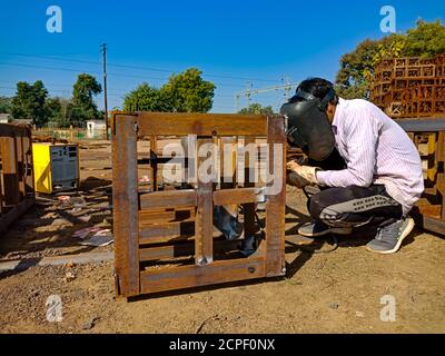 DISTRIKT KATNI, INDIEN - 17. JANUAR 2020: Ein asiatischer Wartungsarbeiter, der während der Eisenbahnbrückenbauarbeiten am Eisennetz schweißen wird. Stockfoto