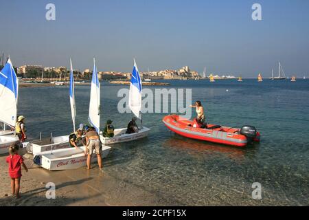 Kinder Matrosen Schule, kleine Segelboote. Studenten des Club Nautique d'Antibes. Kleine Segelboote in der Bucht von Plage du Ponteil. Der Ausbilder mit dem Schleppseil. Stockfoto