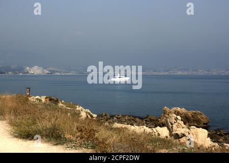 Marina Baie des Anges von Antibes aus gesehen. Wellenförmige Gebäude. Weißes Schiff im ruhigen Meer, raue Steine am Ufer. Stockfoto