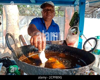 DISTRIKT KATNI, INDIEN - 18. JANUAR 2020: Ein indischer alter Mann, der Samosa in der Ölpfanne an der Straßenecke frittiert. Stockfoto