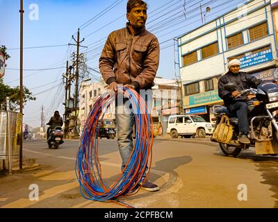 DISTRIKT KATNI, INDIEN - 18. JANUAR 2020: Ein indischer Elektriker bindet Drahtbündel auf der Straße. Stockfoto