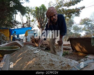 DISTRIKT KATNI, INDIEN - 18. JANUAR 2020: Eine indische Arbeitsverputzung Zementmaterial für den Bau von Parkstuhl auf offenen Bereich Workshop in natürlichen Bac Stockfoto