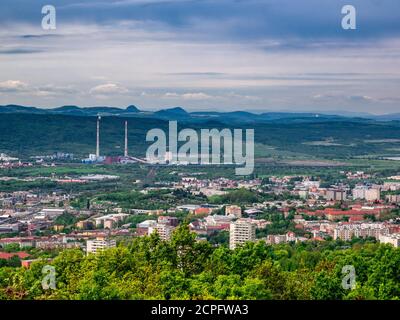 Blick vom Berg auf die Landschaft mit der Stadt Im Tal und in der Fabrik mit zwei hohen Schornsteinen Hinter der Stadt Stockfoto