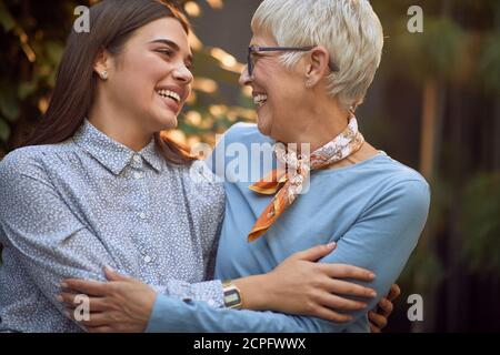 Erwachsene Mutter und Tochter umarmen, einander schauen, lächeln Stockfoto