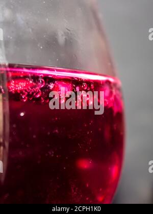 Nahaufnahme von Granatapfelpipetten in einem roten Gin mit Granatapfelgeschmack und Tonic-Cocktail Stockfoto