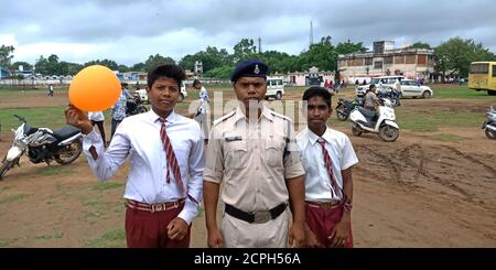 DISTRIKT KATNI, INDIEN - 15. AUGUST 2019: Indischer Schulschüler mit Polizeimann, der auf dem städtischen Spielplatz für nationale Unabhängigkeitstag-Veranstaltungen steht. Stockfoto
