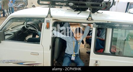 DISTRIKT KATNI, INDIEN - 17. AUGUST 2019: Ein indischer Schuljunge sitzt auf dem Van nach verlassen Seitenstraße für den Transport auf dem Boden. Stockfoto