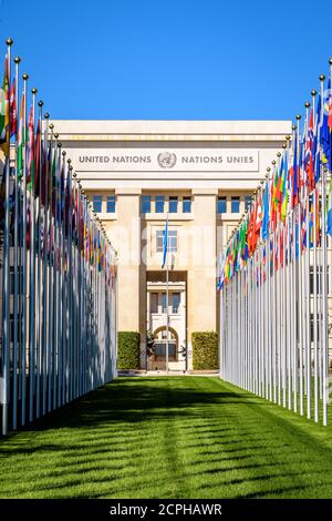 Vorderansicht der Flaggenallee und Fassade des Nationenpalastes, Heimat des Büros der Vereinten Nationen in Genf, Schweiz, an einem sonnigen Sommertag Stockfoto