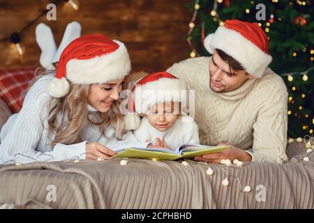 Happy Family liest ein Buch zu Weihnachten. Stockfoto