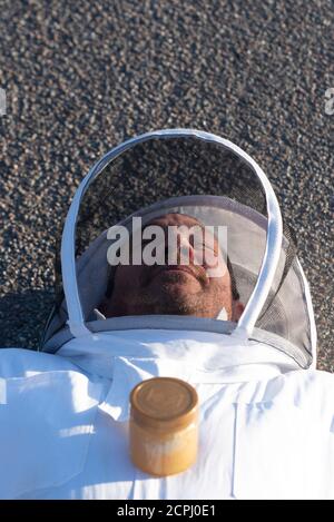 Imker liegt auf einer asphaltierten Straße Stockfoto