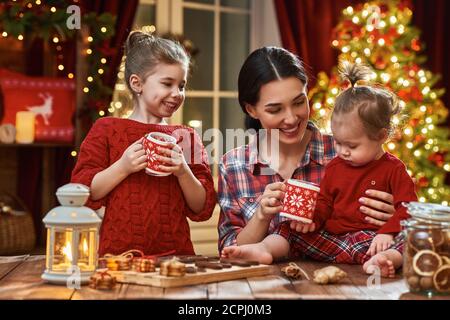 Frohe Weihnachten und frohe Feiertage. Zeit der Familie Teeparty. Mutter und ihre Kinder Töchter trinken warmen Tee mit Weihnachtsplätzchen. Stockfoto