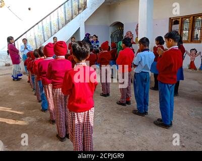 DISTRIKT KATNI, INDIEN - 13. JANUAR 2020: Indische Dorfschulkinder beten zusammen im offenen Innenhof. Stockfoto