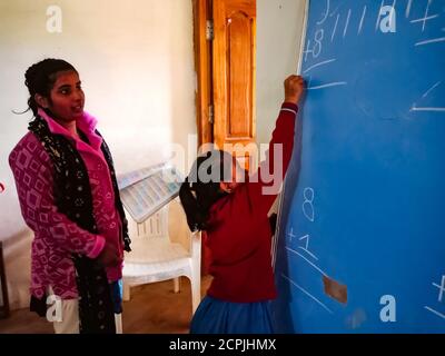 DISTRIKT KATNI, INDIEN - 13. JANUAR 2020: Indisches Dorfschulmädchen, das im Klassenzimmer auf schwarzes Brett schreibt. Stockfoto