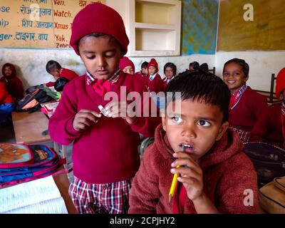 DISTRIKT KATNI, INDIEN - 13. JANUAR 2020: Indische Dorfschulkinder kauen Bleistift im Klassenzimmer. Stockfoto