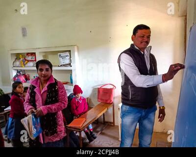 BEZIRK KATNI, INDIEN - 13. JANUAR 2020: Indische Dorfschule männlichen Lehrer schreiben auf Tafel im Klassenzimmer. Stockfoto