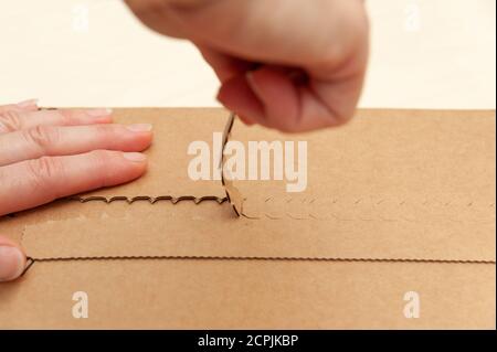 Versandkarton mit den Händen öffnen. Seitenansicht. Nahaufnahme. Stockfoto